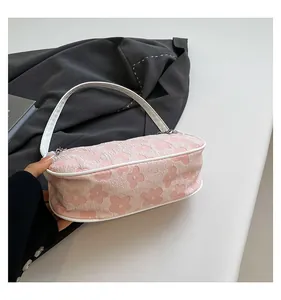 Detailed close-up of pink embossed floral texture and white handle on a small handbag