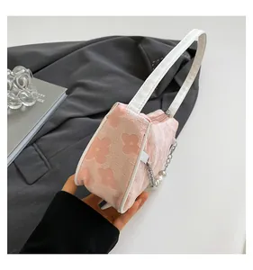 Detail of pink floral woven shoulder bag featuring textured fabric and pearl chain charm