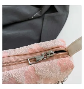Macro detail of pink floral jacquard fabric with silver zipper on women's handbag