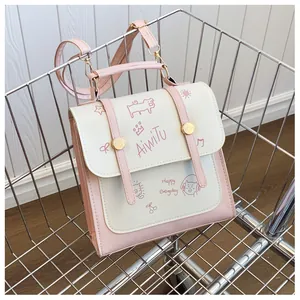 Dettaglio dello zaino rosa e bianco con motivo gatto e chiusura a fibbia magnetica