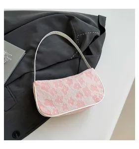 Close-up of pink floral textured fabric underarm bag on a grey blazer background