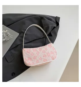 Detail of pink floral jacquard shoulder bag with white leather trim on gray blazer