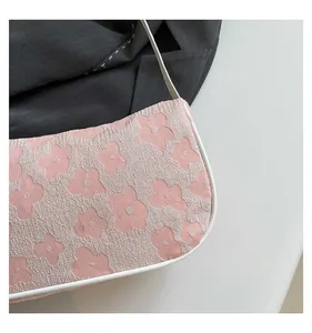 Close-up of pink floral jacquard fabric and white leather piping on a shoulder bag