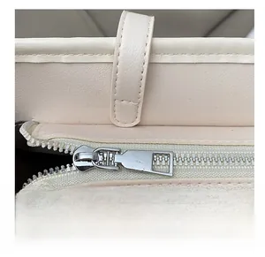 Détail de la fermeture éclair argentée et des coutures sur le sac fourre-tout beige