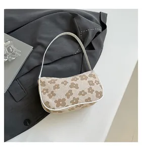 Detail of floral woven beige shoulder bag with brown patterns and white trim on a suit jacket