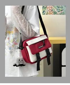 Detail of red and white canvas messenger bag with a buckle and small octopus plush charm