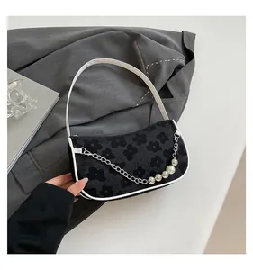 Close-up of woven floral shoulder bag with pearl chain detail and faux leather trim
