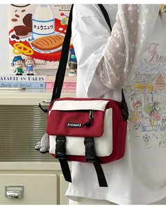 Detail of red and white canvas messenger bag with double buckles and plush charm