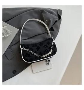 Detail of woven floral shoulder bag with pearl chain and smartphone for size reference