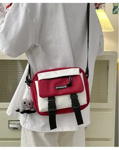Detail of red and white canvas messenger bag with double buckles and octopus plush charm
