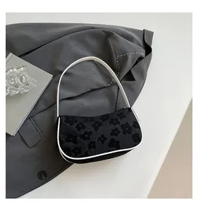 Close-up of small white daisy pattern on a black fabric shoulder bag with white leather trim