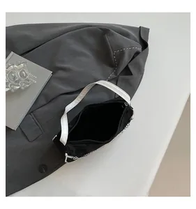Detail view of black and white handbag with silver chain and pearl charm over grey suit