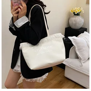 Détail d'un sac cabas en toile blanche avec bordures en dentelle et lettrage imprimé