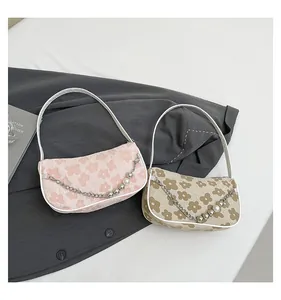 Detail of floral knit baguette bags with pearl chains and sleek leather piping finish