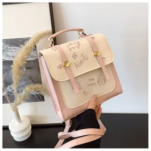 Dettaglio della stampa cartoon su borsa in pelle crema e rosa con fibbie decorative