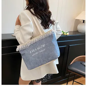 Détail du sac cabas en denim bleu avec bordure en dentelle blanche et logo brodé