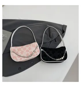 Detail of floral woven shoulder bags with pearl chains in pink and black colors