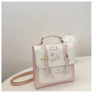 Dettaglio della borsa in ecopelle rosa e bianca con graffiti di cartoni e fibbie dorate