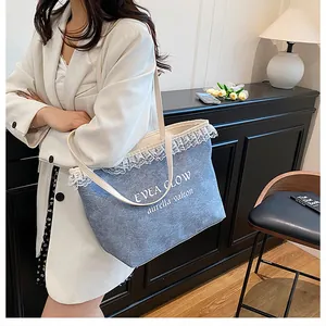 Détail d'un cabas en jean bleu avec bordure en dentelle blanche et logo EVEA GLOW