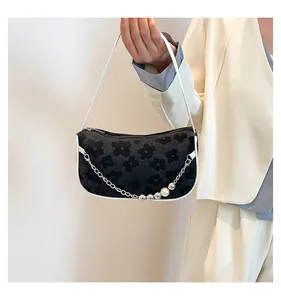 Close-up of velvet woven shoulder bag featuring pearl chain and floral texture detail