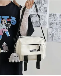 Detail of off-white canvas messenger bag with black buckles and plush octopus charm