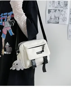 Close-up of white canvas shoulder bag with black buckles and cute octopus plush charm