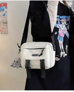 Detail view of white canvas crossbody bag with octopus charm and plastic buckle closure