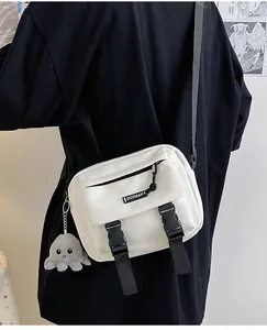 Detail of white canvas crossbody bag featuring black buckles and grey octopus plush charm