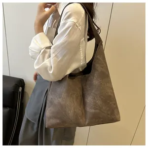 Close-up of a large dark grey hobo tote bag with vintage texture on a model's shoulder