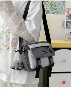 Detail of grey color-block messenger bag with dual buckles and cute octopus plush charm
