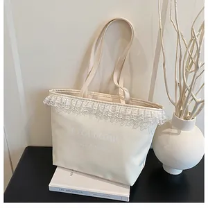 Détail d'un sac cabas crème avec bordure en dentelle blanche et lettrage artistique élégant