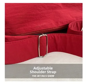 Detail of the adjustable fabric shoulder strap and silver metal buckle on the red nylon bag
