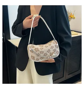 Detail of light brown woven shoulder bag with floral patterns and pearl chain strap