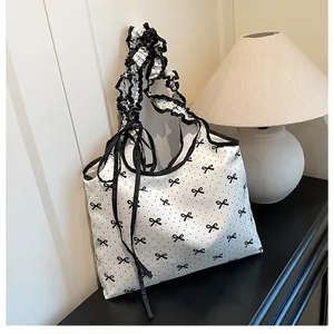 Detail van een witte canvas tas met zwarte strikjes en ruches aan de handvaten