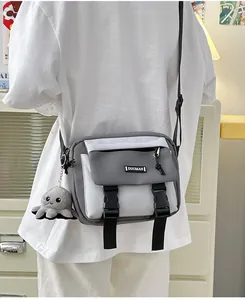 Gray and white nylon crossbody bag with dual buckles and a plush octopus charm accessory