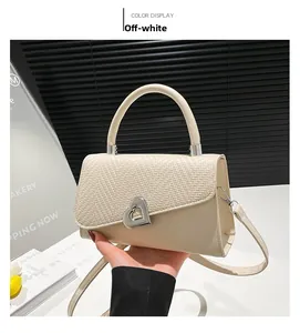 Detail van gebroken witte crossbodytas met geweven flap en zilveren hartsluiting