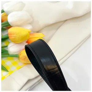 Détail d'une bandoulière en cuir noir avec des coutures précises et grain naturel