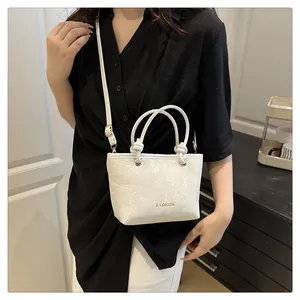 Détail du sac seau blanc avec texture serpent et logo doré FASHION en gros plan