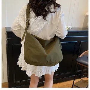 Olive green large capacity canvas crossbody bag shown on a model in a minimalist setting