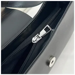 Détails du zip métallique argenté et du fermoir magnétique sur un sac à main noir élégant