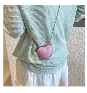 Détail d'un sac coeur à paillettes roses avec bandoulière chaîne sur un mannequin