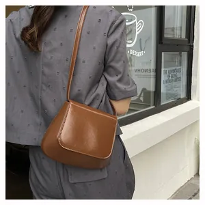 Brown leather saddle bag shown on shoulder with adjustable strap and vintage look