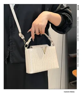 Detailed view of cream-white crocodile texture handbag with gold V-shaped metal clasp