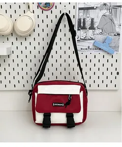 Detail of red and white canvas crossbody bag with adjustable strap and DUOMAN brand tag