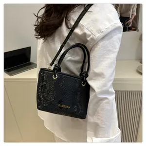Détail du sac bandoulière noir texture serpent avec détails dorés et logo mode