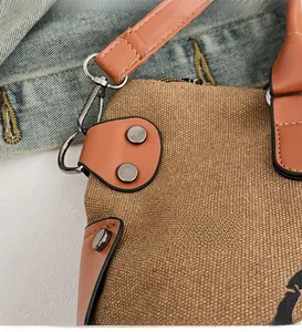 Close-up of canvas texture, brown leather reinforcement patches, and metal rivets