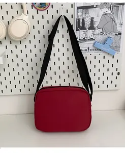 Detail view of the red rectangular canvas crossbody bag with adjustable black strap
