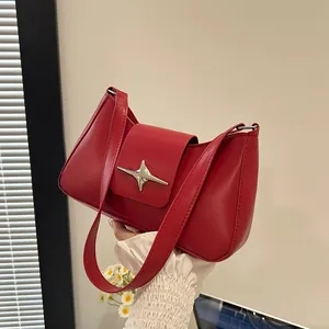 Détail du sac à main en cuir rouge avec boucle étoile argentée et design structuré