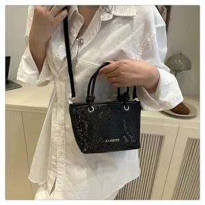 Détail du mini sac noir texture serpent avec texte FASHION doré et longue bandoulière
