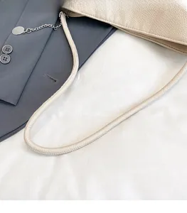 Détails du cuir grainé blanc crème et des fines bandoulières rondes cousues du sac à main